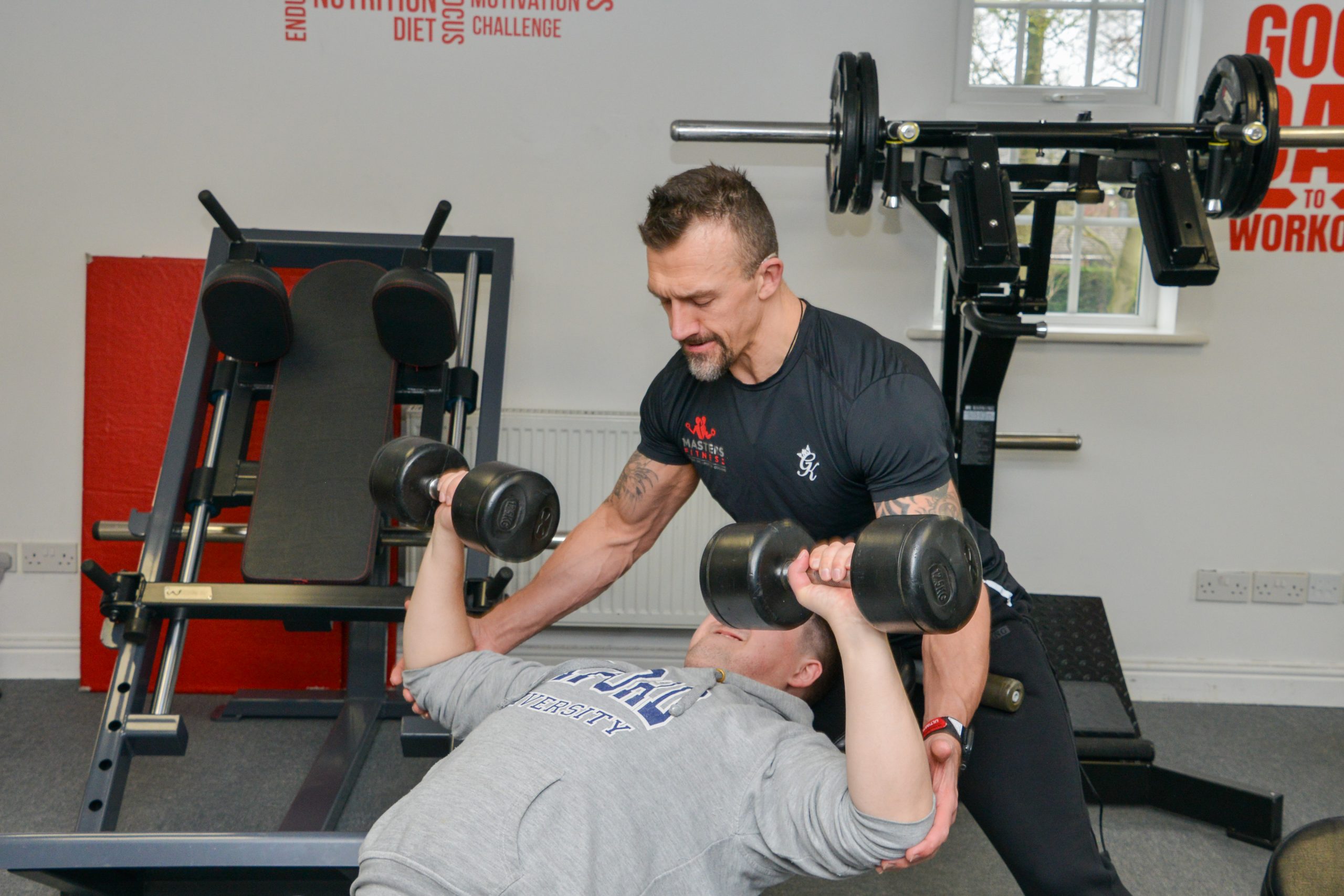 A Masters Fitness trainer spotting a client on the dumbbell press