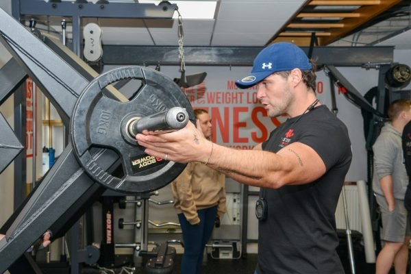 Gabe Storey, personal trainer, loading a plate on a machine in the gym