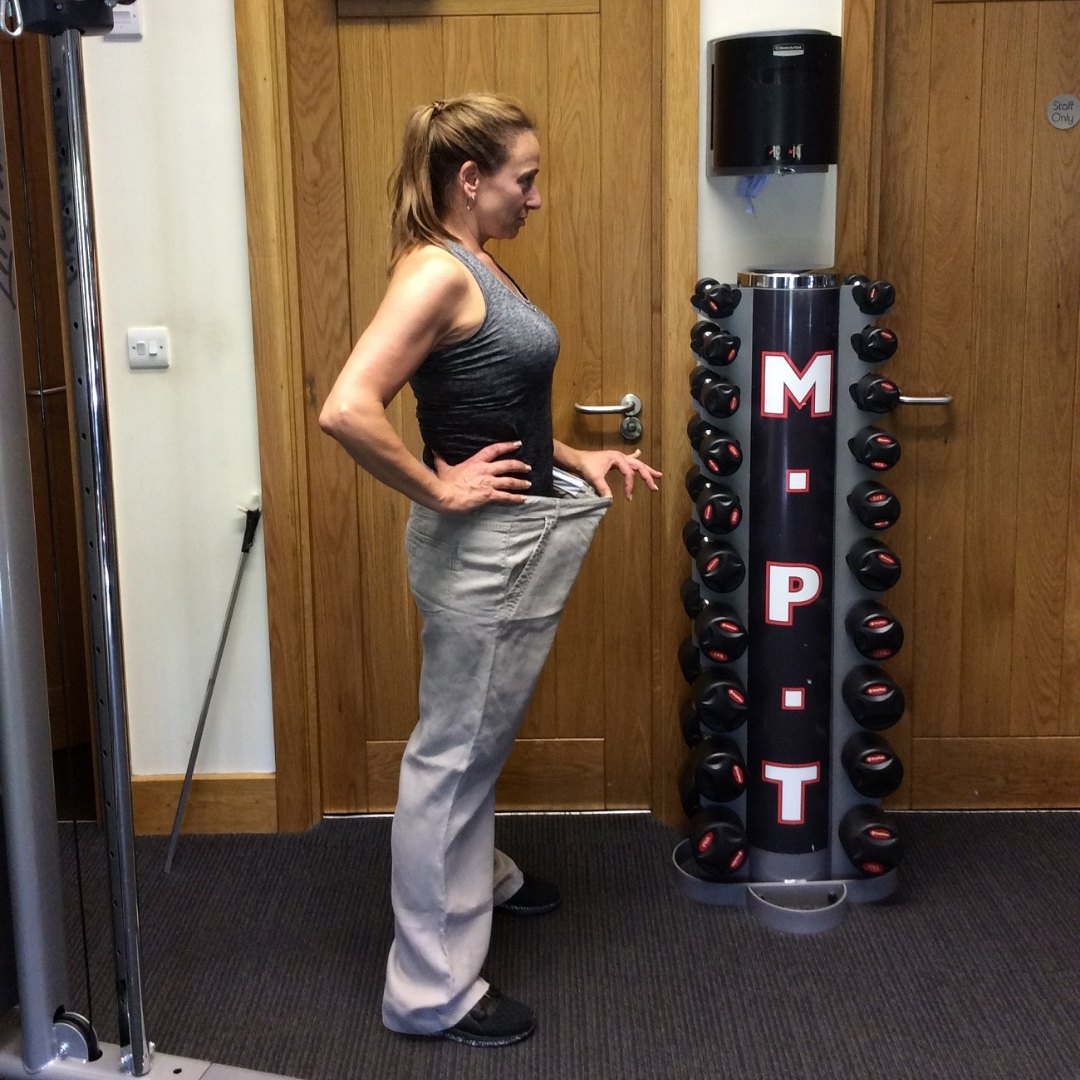 A Masters Fitness client holding out the waistband of her old trousers after her transformation
