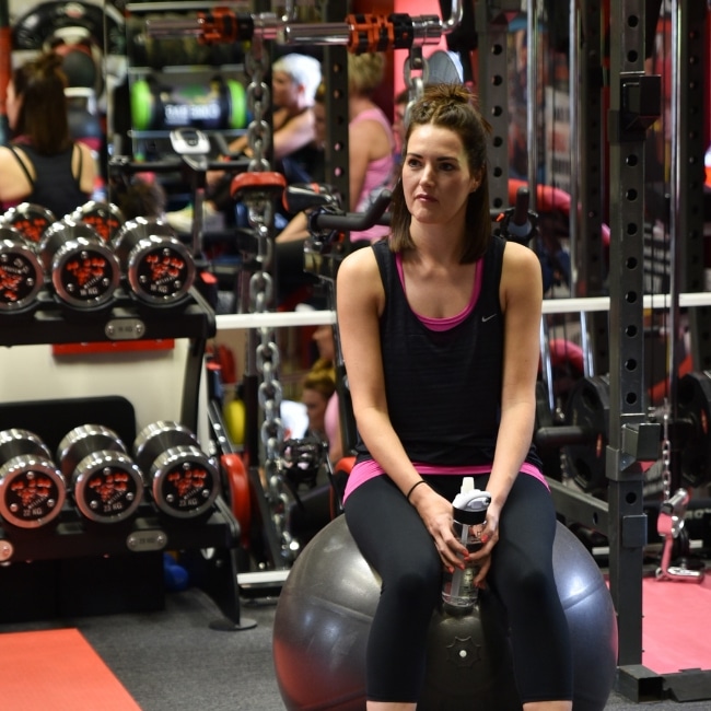 A member taking a break on a gym ball in the free weights area