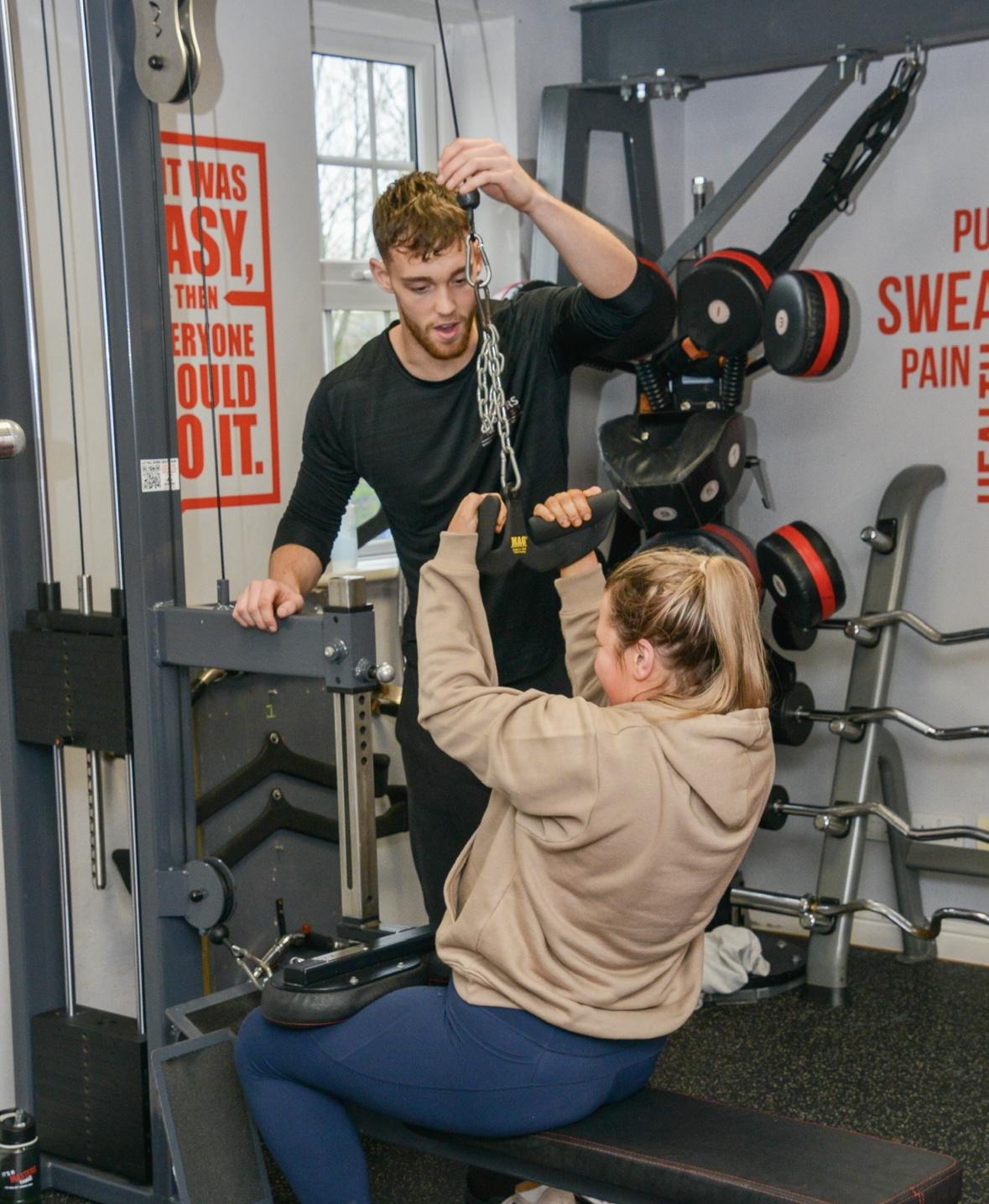 A Masters Fitness personal trainer coaching a client on the cable pulldown