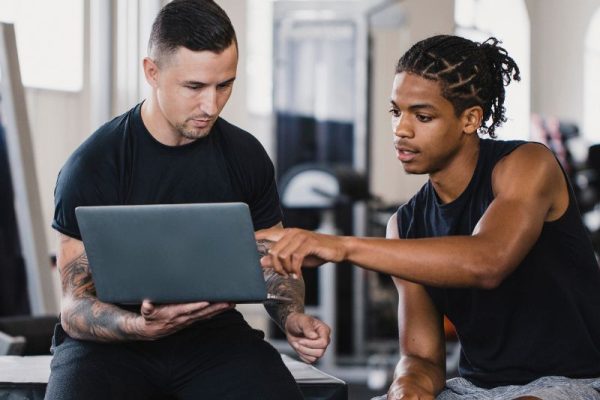 A trainer going through a plan on a laptop with a client