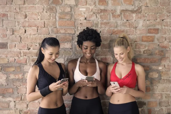 Three women looking at their phones after a workout