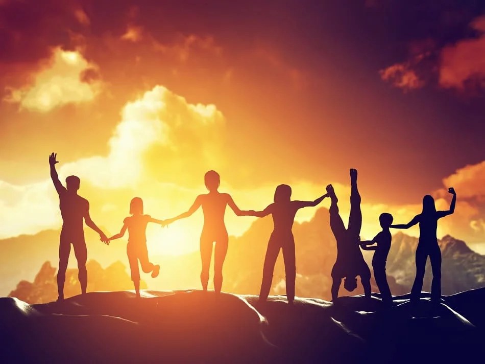 A family holding hands in silhouette on a hilltop at sunset, arms raised