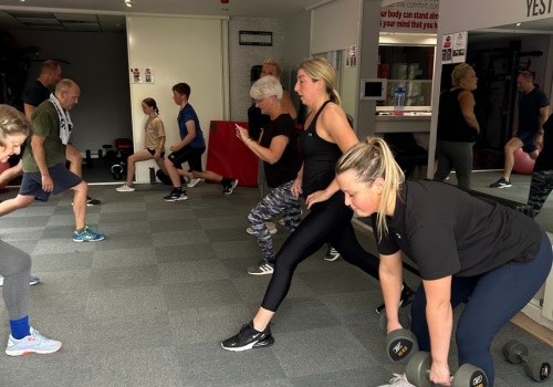 A mixed group class doing lunges and dumbbell work