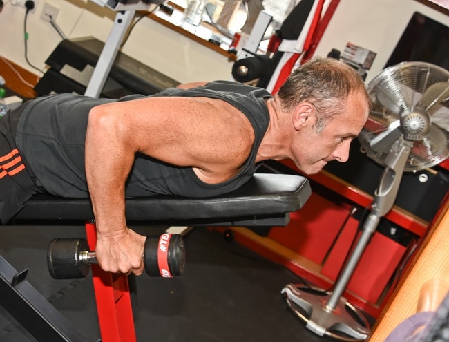 A male client doing a chest-supported dumbbell row