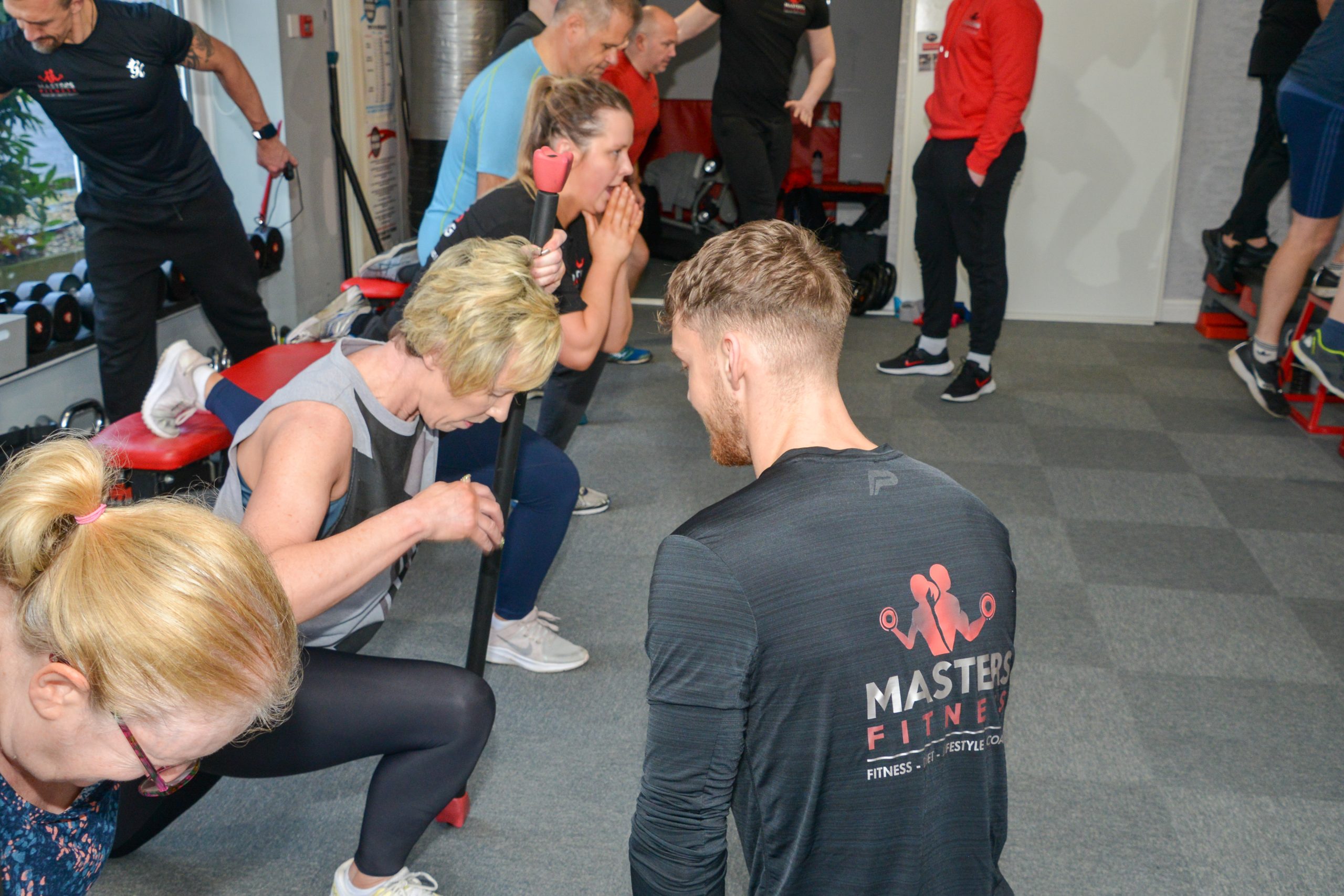 A Masters Fitness trainer coaching a group session on the gym floor