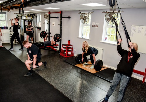 A bootcamp class using kettlebells, barbells and suspension trainers