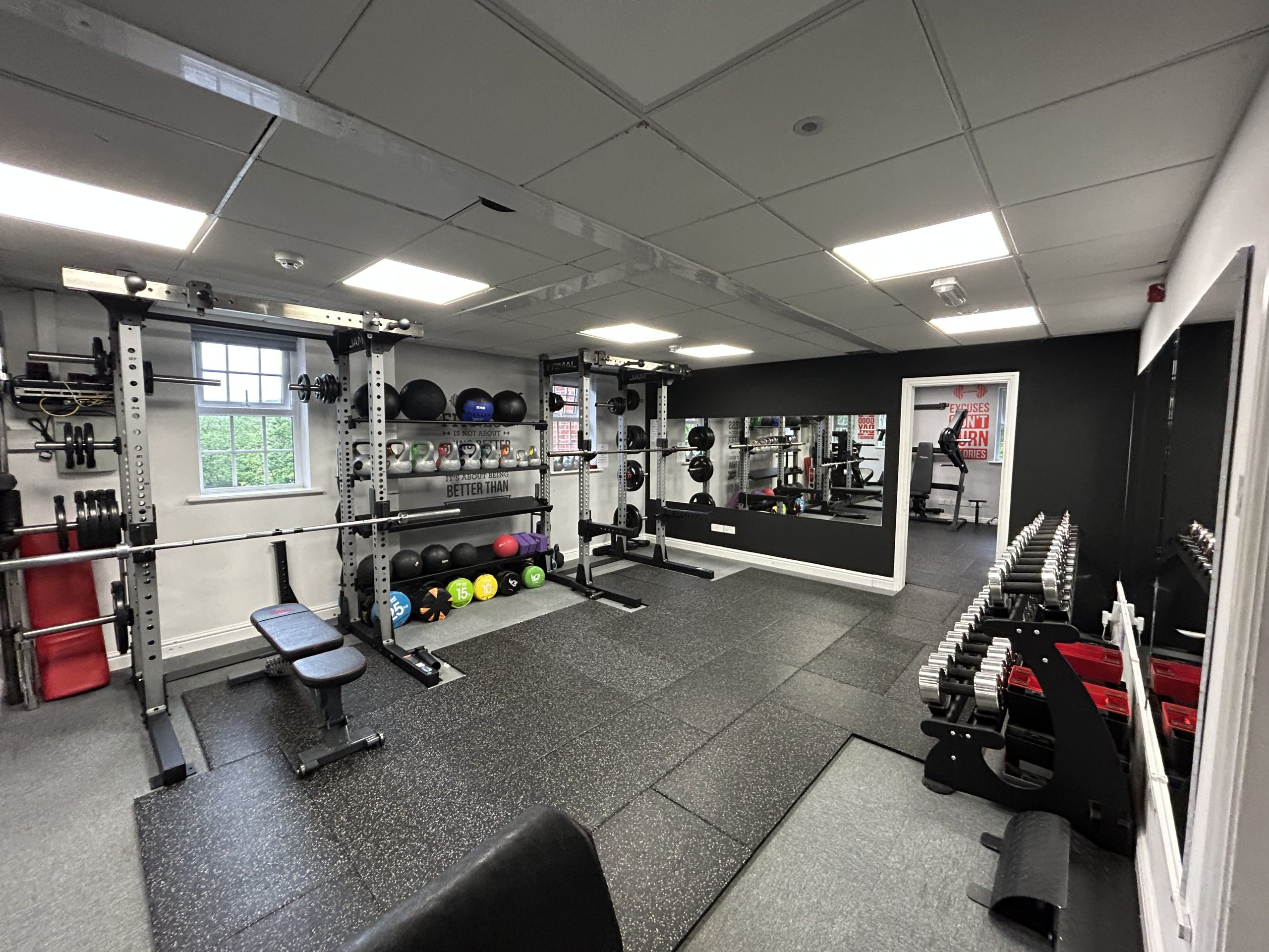 A gym floor with benches, racks and medicine balls
