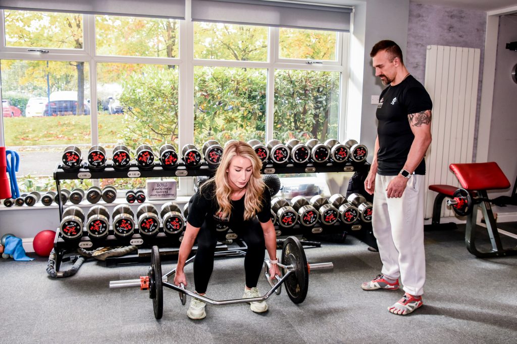 A trainer coaching a client through a trap bar deadlift