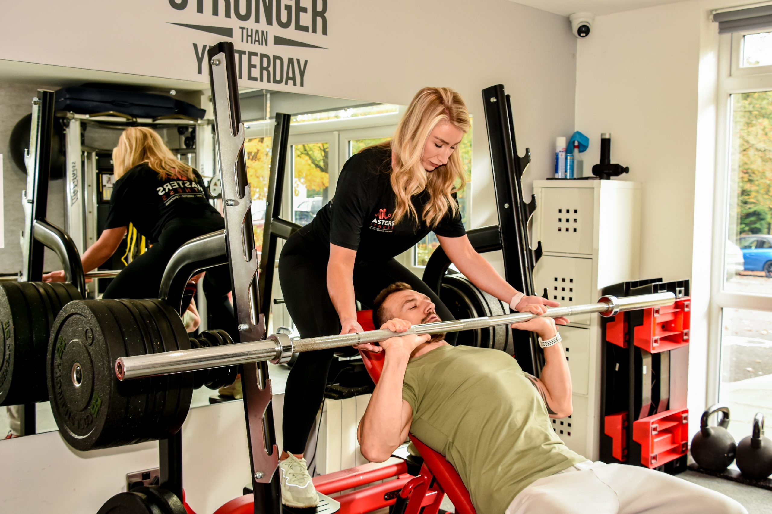A personal trainer spotting a client on the incline bench press