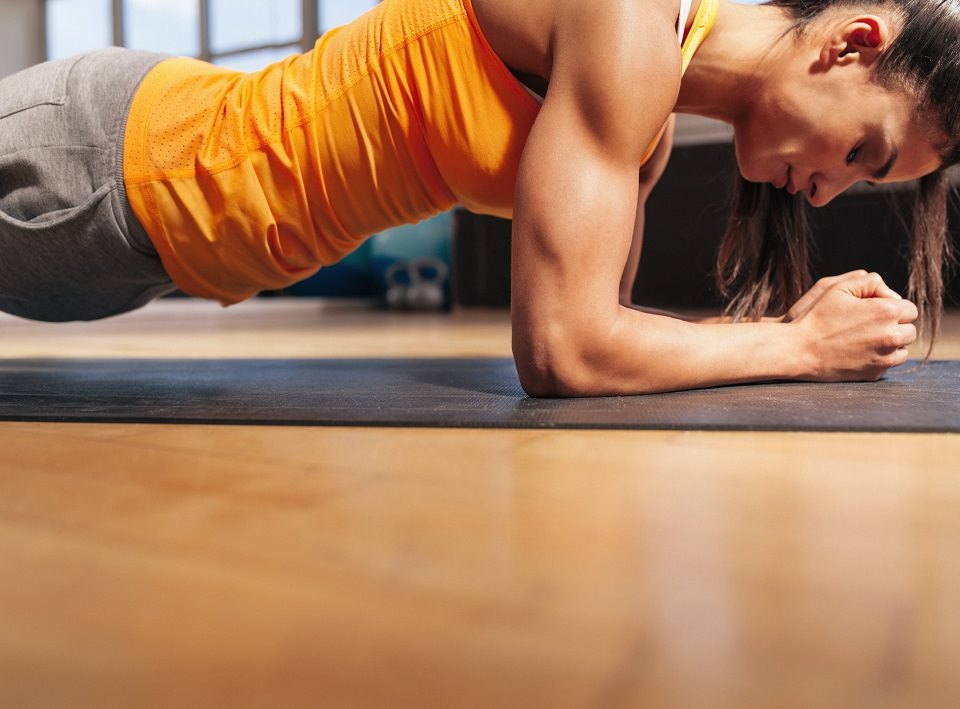 A woman holding a forearm plank on an exercise mat