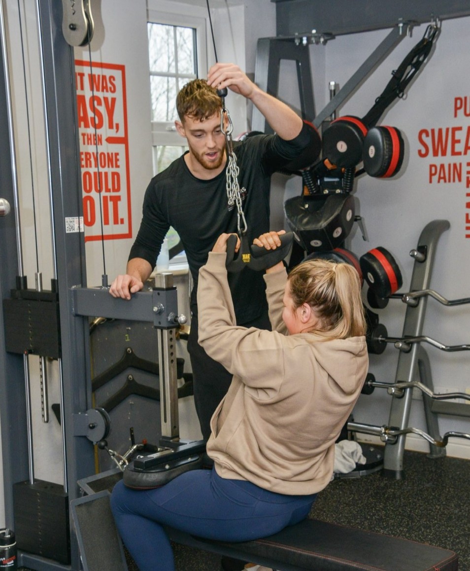 A trainer guiding a client through a cable pulldown